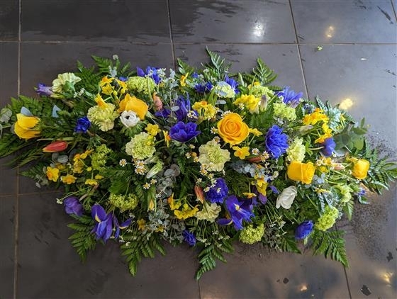 Vibrant yellow and blue casket spray